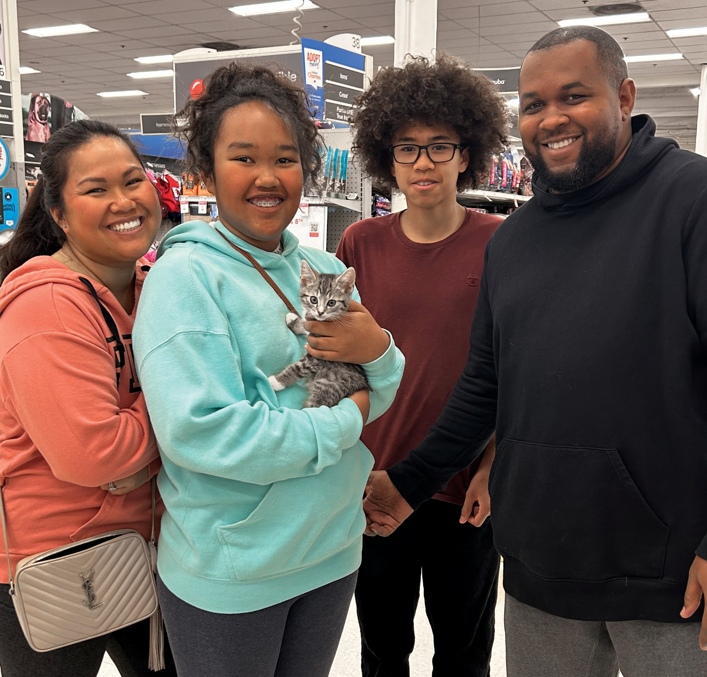 Family of four poses with their new adopted kitten