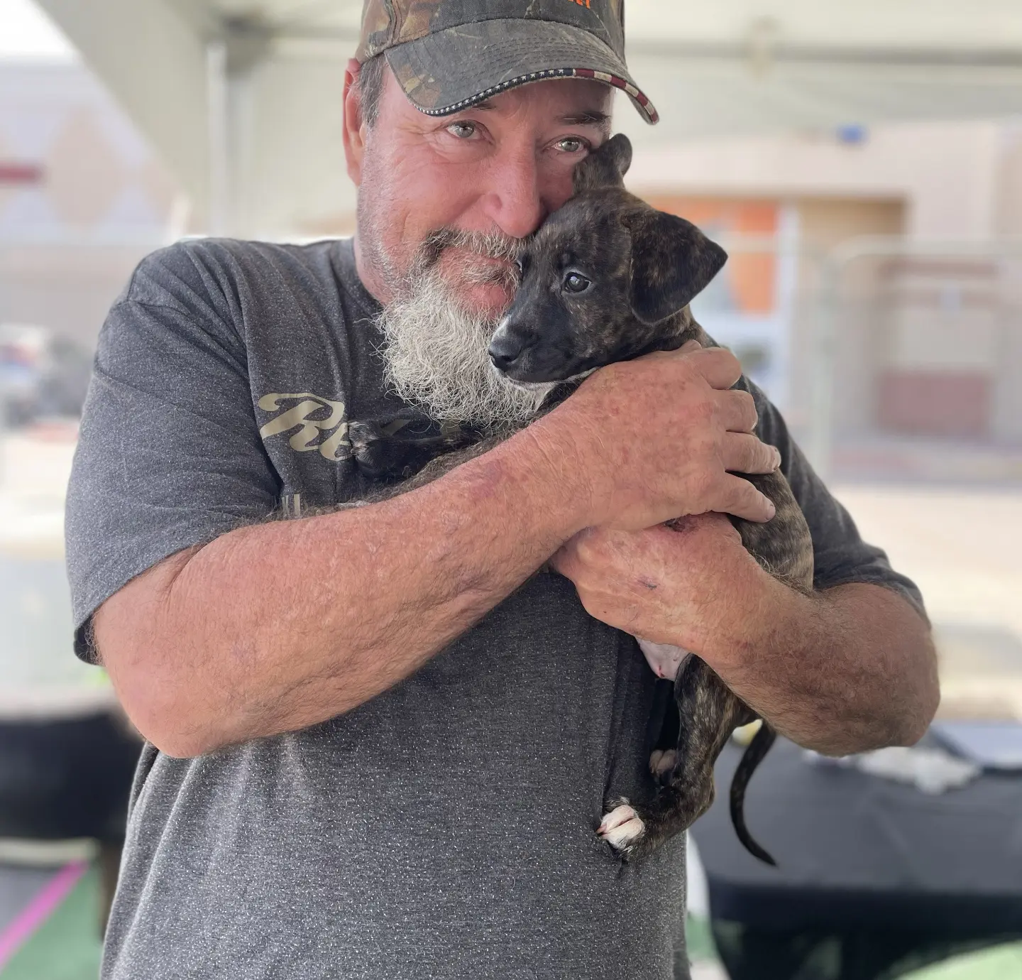 a man smiles at the camera while he cuddles a puppy