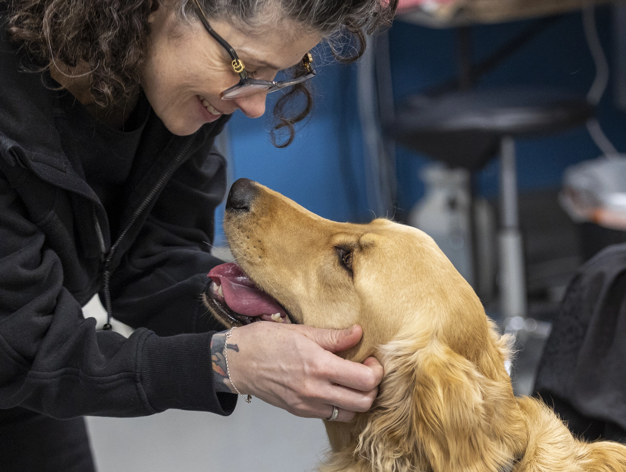 a woman wearing glasses holding the face of a golden retriever